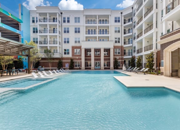 Sparkling swimming pool with Era building in the background at Era Apartments in Denton, TX
