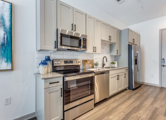 Model Studio kitchen with stainless steel appliances and white cabinetry at Era Apartments in Denton, TX