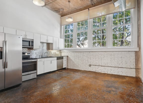a kitchen with white cabinets and stainless steel appliances and a large window