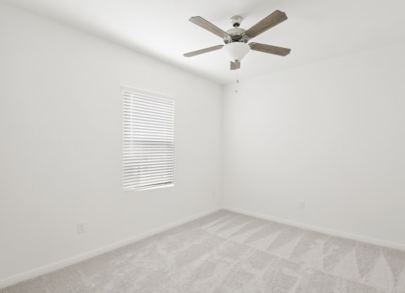 a bedroom with white walls and a ceiling fan