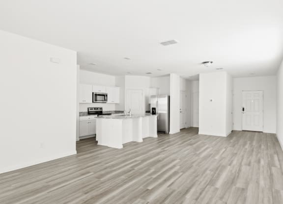 a kitchen and living room in a spcious area with wood floor