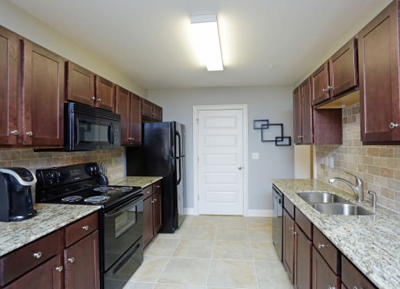 Modern kitchen with black appliances and granite counter tops at Grand Reserve at Pelham in Pelham, AL