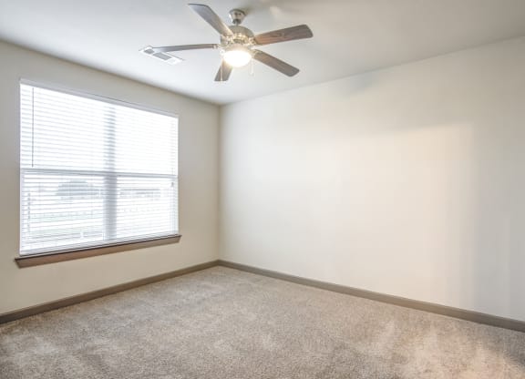 an empty room with a ceiling fan and a window