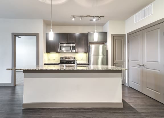 an empty kitchen with a large island with a granite counter top