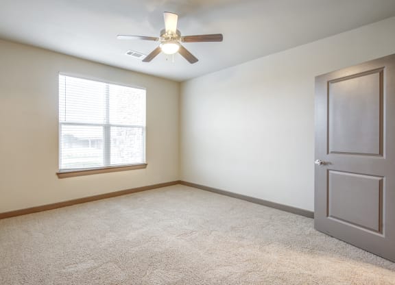an empty room with a ceiling fan and a window