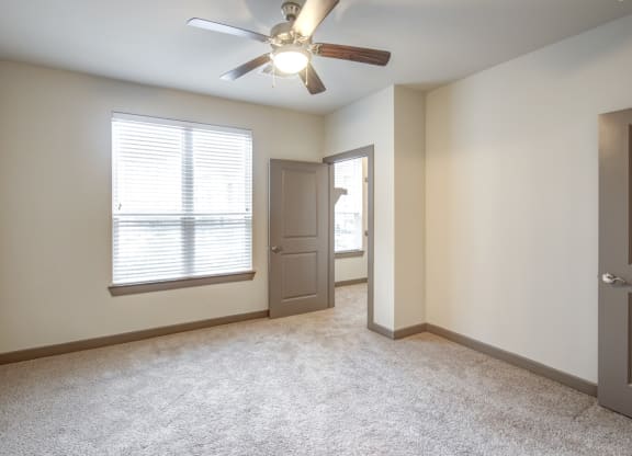 an empty living room with a ceiling fan and a window