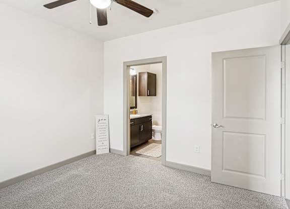 A bedroom with white walls, a closet, and a fan on the ceiling at GreenVue Apartments in Richardson, TX