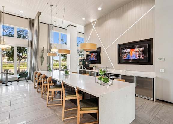 Clubhouse kitchen with a long island and wooden chairs at GreenVue apartments in Richardson, TX