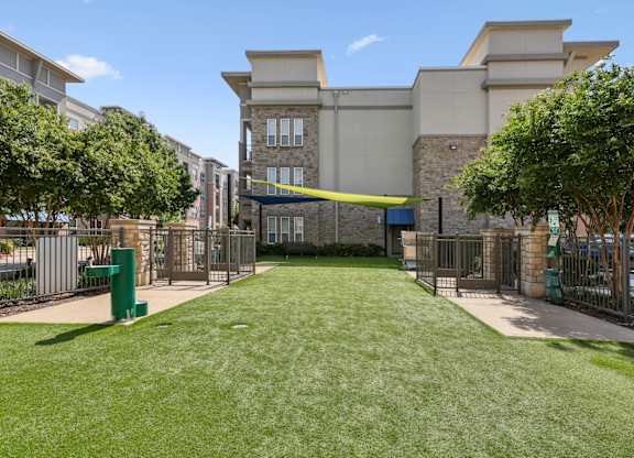 Dog park with a large grassy area and water fountain at GreenVue apartments in Richardson, TX