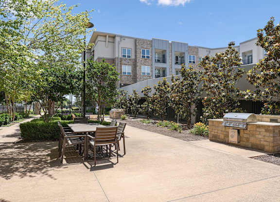 A courtyard with a table and chairs and grilling station at GreenVue apartments in Richardson, TX