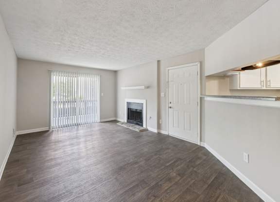 A living room with a fireplace and wooden floors at Gwinnett Square Apartments in Duluth, GA