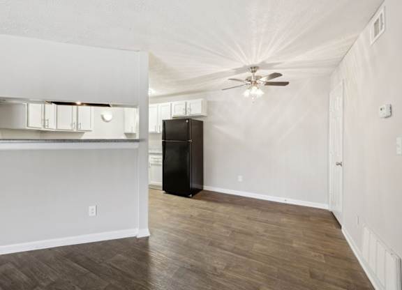 A dining room with a ceiling fan leading into the kitchen at Gwinnett Square Apartments in Duluth, GA