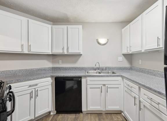 A kitchen with white cabinets and black appliances at Gwinnett Square Apartments in Duluth, GA