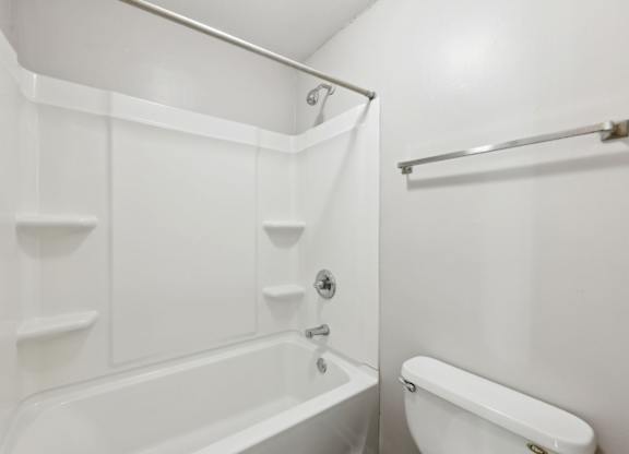 A white bathroom with a tub and toilet at Gwinnett Square Apartments in Duluth, GA