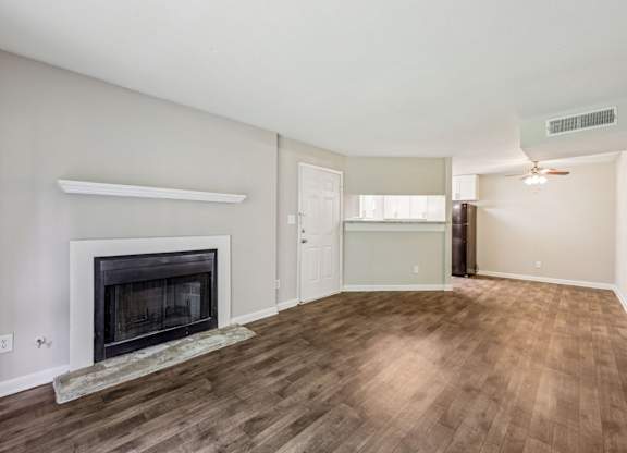 A living room with a fireplace that leads into the dining and kitchen area at Gwinnett Square Apartments in Duluth, GA