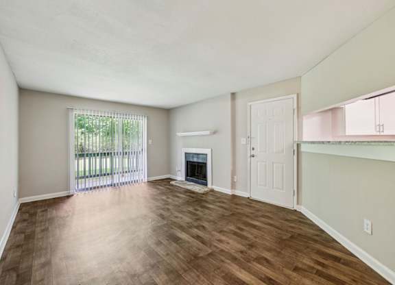 A living room with a fireplace and a glass door leading to a balcony at Gwinnett Square Apartments in Duluth, GA