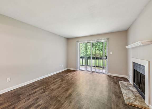 A living room with a fireplace and a sliding glass door leading to a balcony at Gwinnett Square Apartments in Duluth, GA