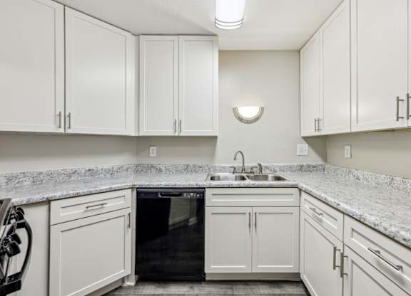 A kitchen with white cabinets and a black dishwasher at Gwinnett Square Apartments in Duluth, GA