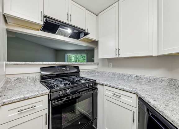 A kitchen with a black stove top oven and white cabinets at Gwinnett Square Apartments in Duluth, GA