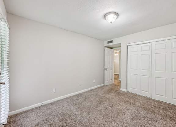 A bedroom with a closet and carpet at Gwinnett Square Apartments in Duluth, GA