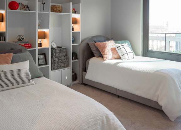 3 bedroom model second bedroom with two twin size beds and a bookcase at The Hamilton apartments in Dallas, TX