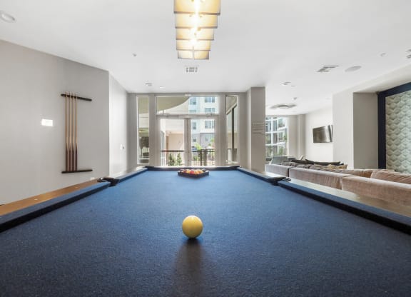 a game room with a blue pool table and a yellow ball on top of it at Harlow River Oaks in Houston, TX