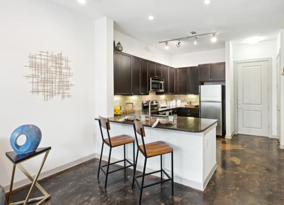 Model kitchen with a counter top with stools at Harlow River Oaks in Houston, TX