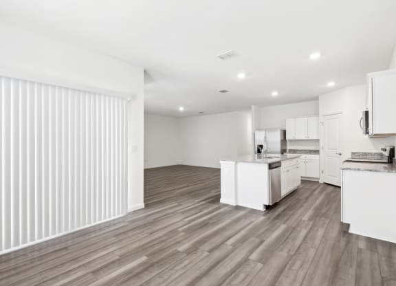 a kitchen and living room with wood floor and white walls