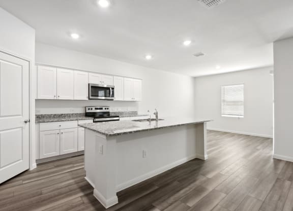 an open kitchen with white cabinets and granit counter top