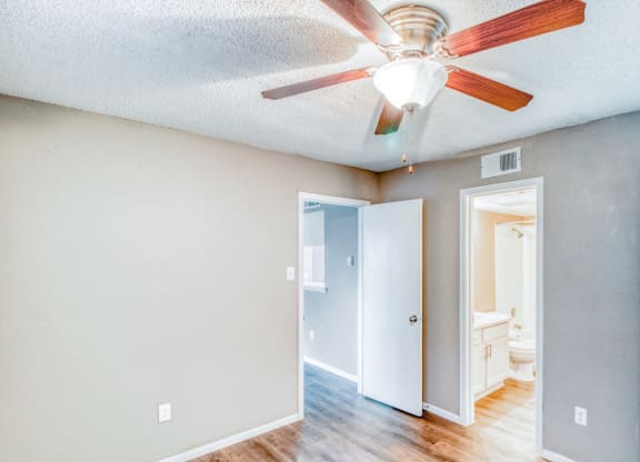 Unfurnished apartment bedroom with ceiling fan and private bathroom at Hillside Creek Apartments in Austin, TX