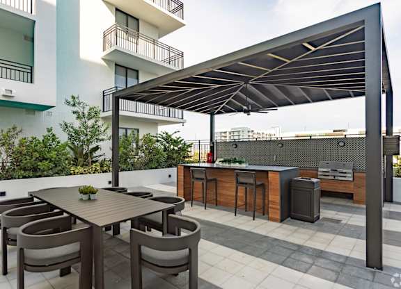 Outdoor grilling station with two BBQ grills and ample seating under a pergola at Hollywood Heights on the Boulevard Luxury Apartments in Hollywood, FL