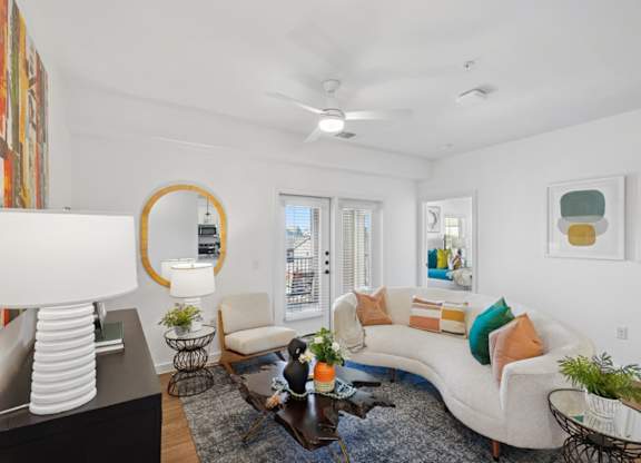 A living room with a white couch, a coffee table, and a mirror.