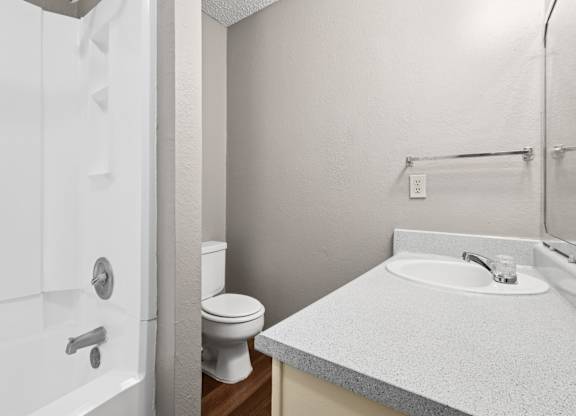 A bathroom with a toilet, sink, and bathtub at Heritage Square Apartments in Waco, TX
