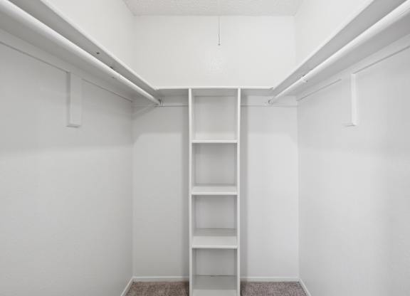 A walk-in closet with built-in shelves and hanging space at Heritage Square Apartments in Waco, TX