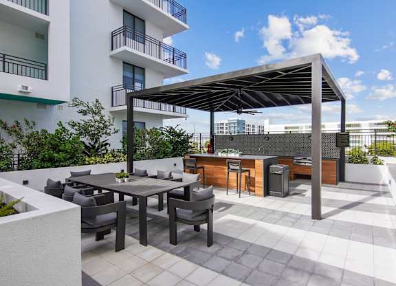 Outdoor grilling station with two BBQ grills and ample seating under a pergola at Hollywood Heights on the Boulevard Luxury Apartments in Hollywood, FL