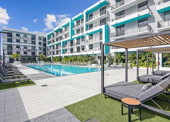 Our beautiful pool surrounded by lounge chairs and lush greenery at Hollywood Heights on the Boulevard Luxury Apartments in Hollywood, FL