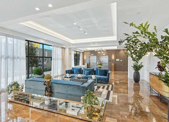 Lobby area with soft blue couches and elevators in the background at Hollywood Heights on the Boulevard Luxury Apartments in Hollywood, FL