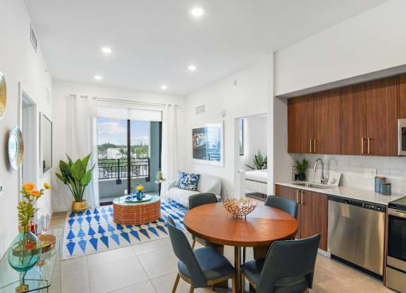 Living room and modern kitchen in our 2-bedroom model with a dining table and chairs  Balcony view of Hollywood Boulevard at Hollywood Heights on the Boulevard Luxury Apartments in Hollywood, FL