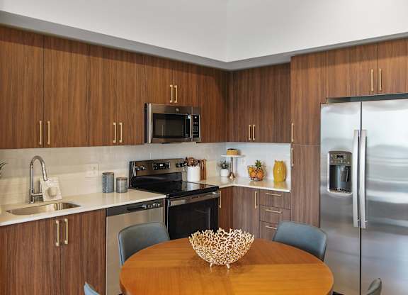 A kitchen with wooden cabinets and a stainless steel refrigerator.