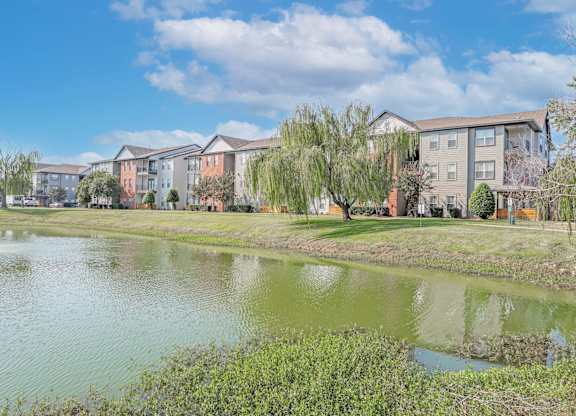 A row of apartment buildings with a pond in front at Ultris Island Park in Shreveport, LA
