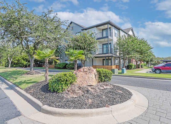 Main entrance road with median and apartment buildings in the background at Ultris Island Park in Shreveport, LA