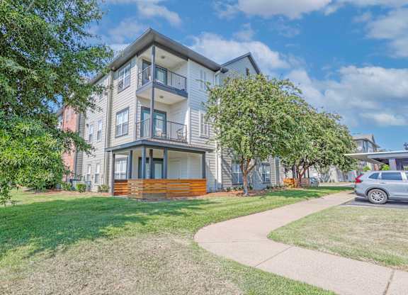 View of apartment exterior with patio and balconies and lush landscaping at Ultris Island Park in Shreveport, LA
