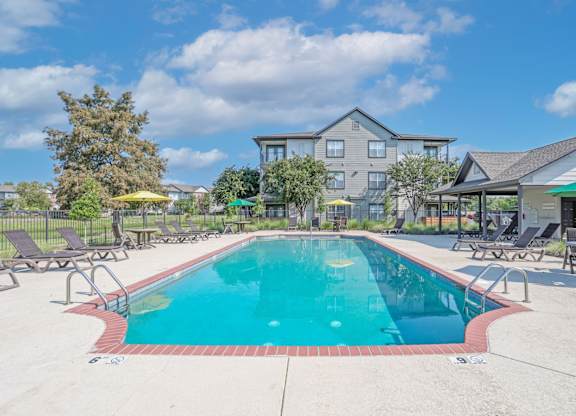 A large swimming pool surrounded by lounge chairs and umbrellas at Ultris Island Park in Shreveport, LA