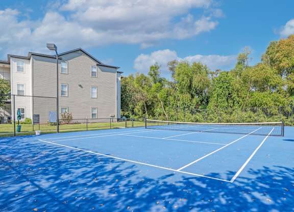 A blue tennis court is surrounded by apartment buildings at Ultris Island Park in Shreveport, LA