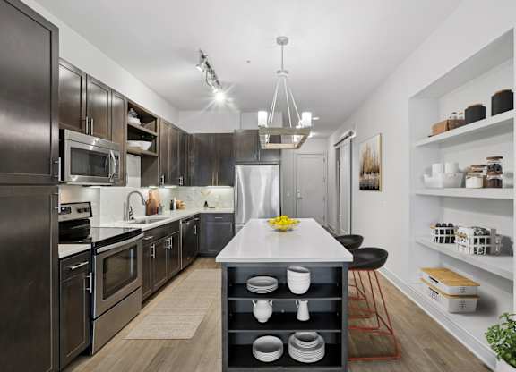 A modern kitchen with dark wood cabinets and a white island at Knox Heights apartments in Dallas, TX