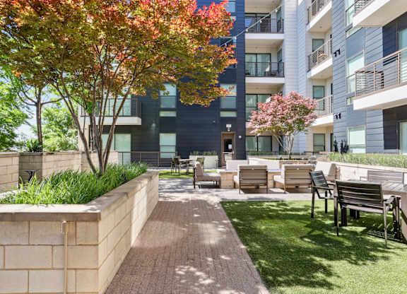 A modern apartment complex with a landscaped outdoor courtyard at Knox Heights Apartments in Dallas, TX