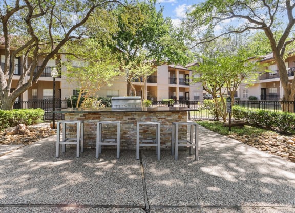 a patio with a table and chairs and trees in the background