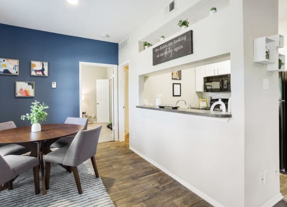 a dining area with a table and chairs and a kitchen in the background
