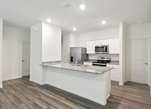 the kitchen with granite countertop and white cabinets