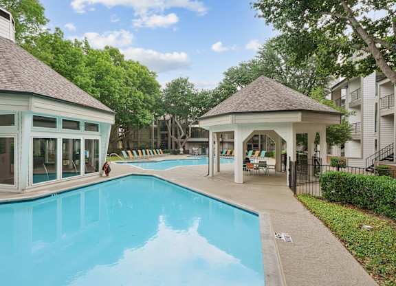 A swimming pool with a pavilion and a person walking.